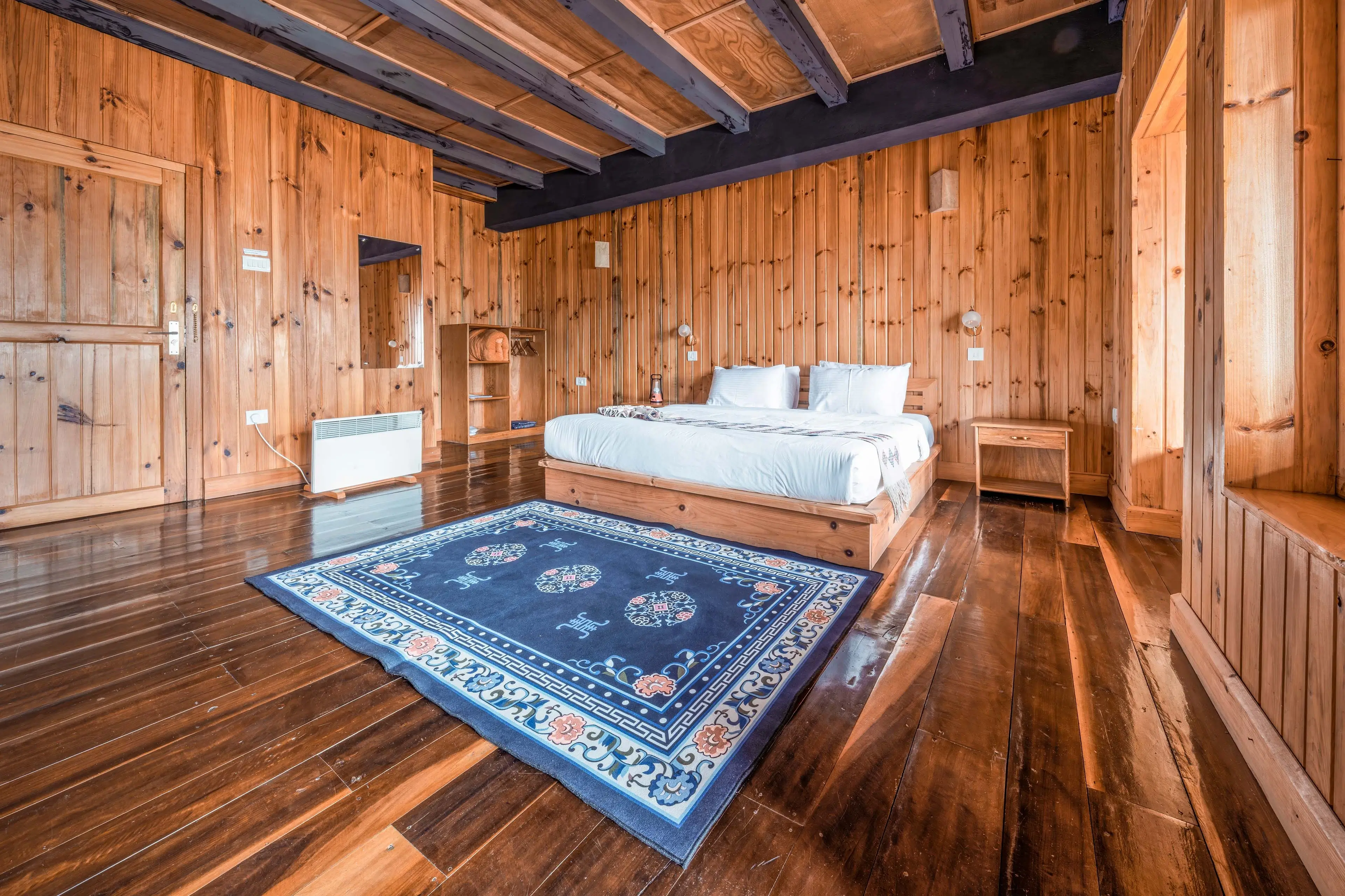A shot of the queen sized bed and the carpet in the foreground